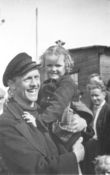Bådebygger Henrik Petersen vender hjem fra eksil i Sverige i maj 1945. På armen har han datteren Anni – selvfølgelig med dannebrogsflag i håret. Foto: Historisk Arkiv Dragør.
