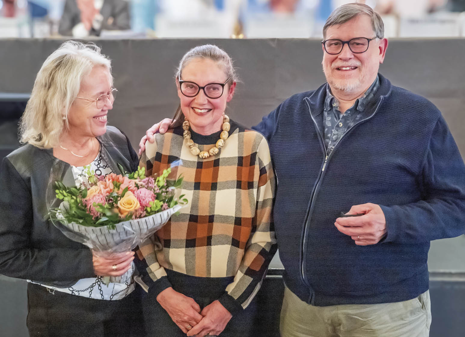 Annette Scheutz (tv.) og Jørn Steen Larsen overrækker blomster og æresnål til Hanne Kirkeberg.