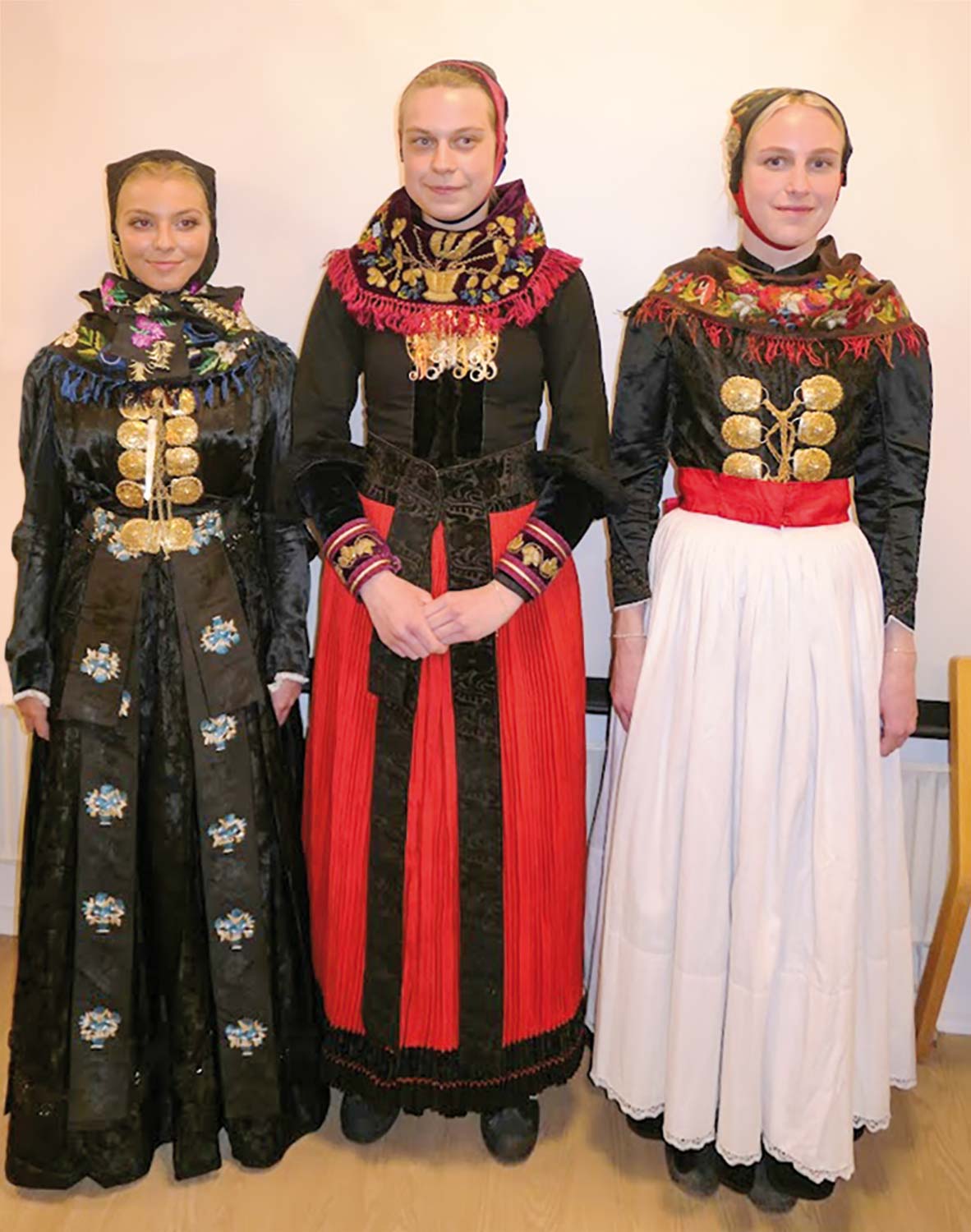 Tre piger lader sig iklæde forskellige udgaver af amagerdragter; Jasmin Plöger Flenø i den sorte festdragt, Julie Gernager Petersen i den røde højtidsdragt og Nanna Gernager Petersen i den hvide ungpigedragt.