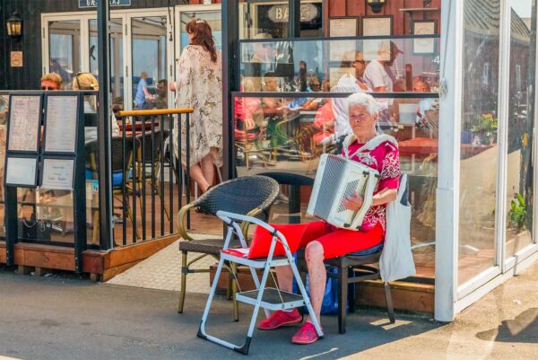 Bente Thers med sin harmonika foran Café Havslapning. Foto: TorbenStender.