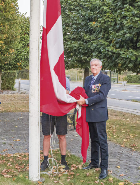 Claus Arboe-Rasmussen stryger Dannebrog ved solnedgang. Foto: TorbenStender.