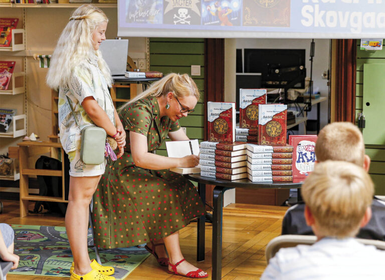 Katrine Skovgaard signerer sin bog Basismagi C. Hun skriver også en lille hilsen i den til de fremmødte børn, som efterfølgende kan tage bogen med hjem. Foto: Maya Schuster.